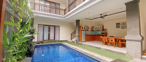 Una piscina techada, una piscina al aire libre, sombrillas