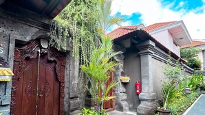 A traditional building with a large wooden door and a small garden area with plants and a fire extinguisher. - De'bharata Bali Villas Seminyak (Seminyak)