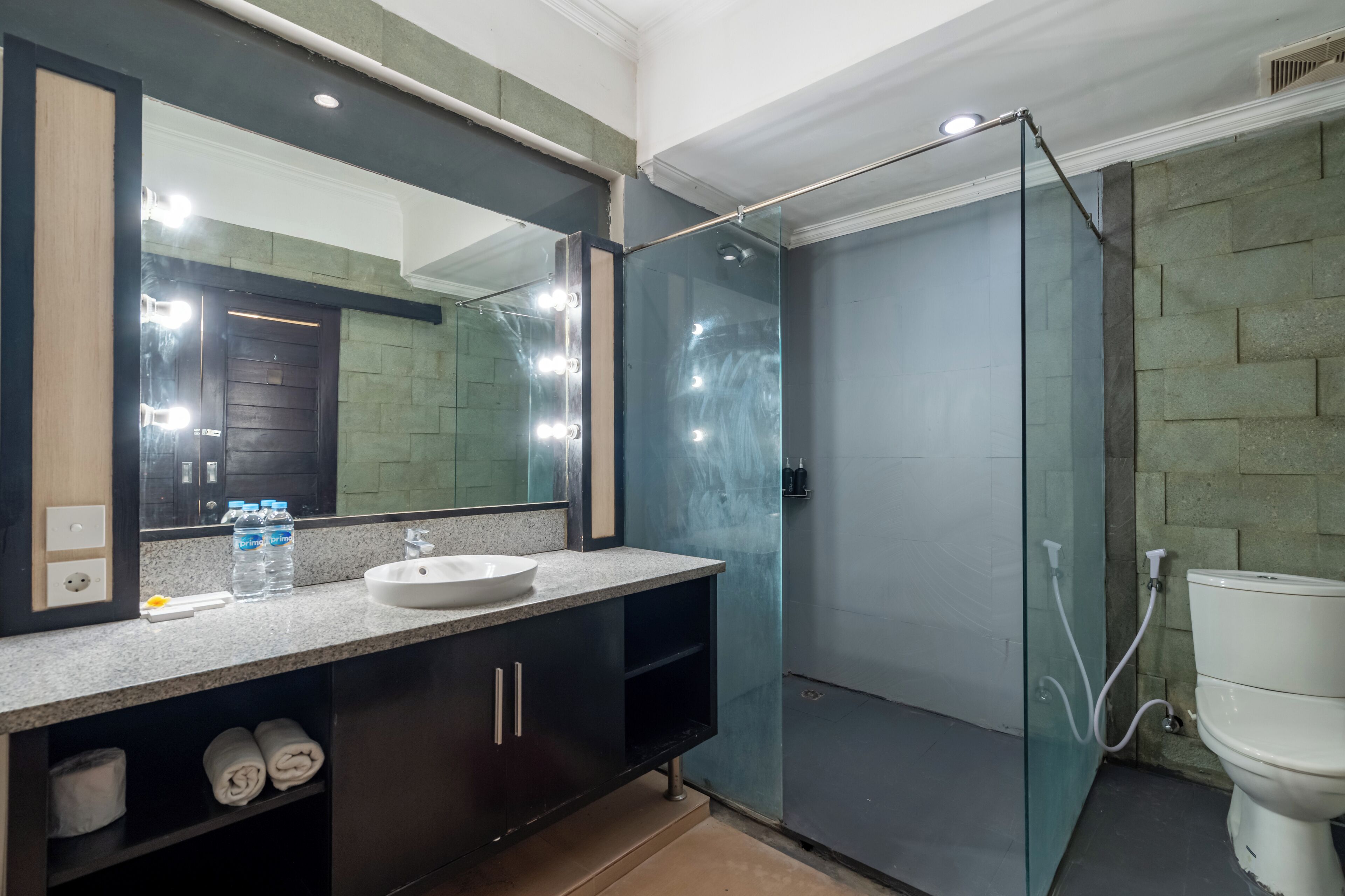 A modern bathroom with a glass-enclosed shower, a large mirror, and a white sink.