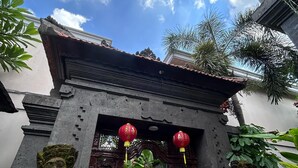 A traditional gate with intricate carvings, red lanterns, and a stone statue. - De'bharata Bali Villas Seminyak (Seminyak)