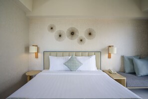 A hotel room with a large bed, two bedside tables, a nightstand, a wall-mounted lamp, and a decorative wall piece.