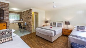 A hotel room with a bed, bedside tables, a desk with a chair, a small kitchenette, and a bathroom.