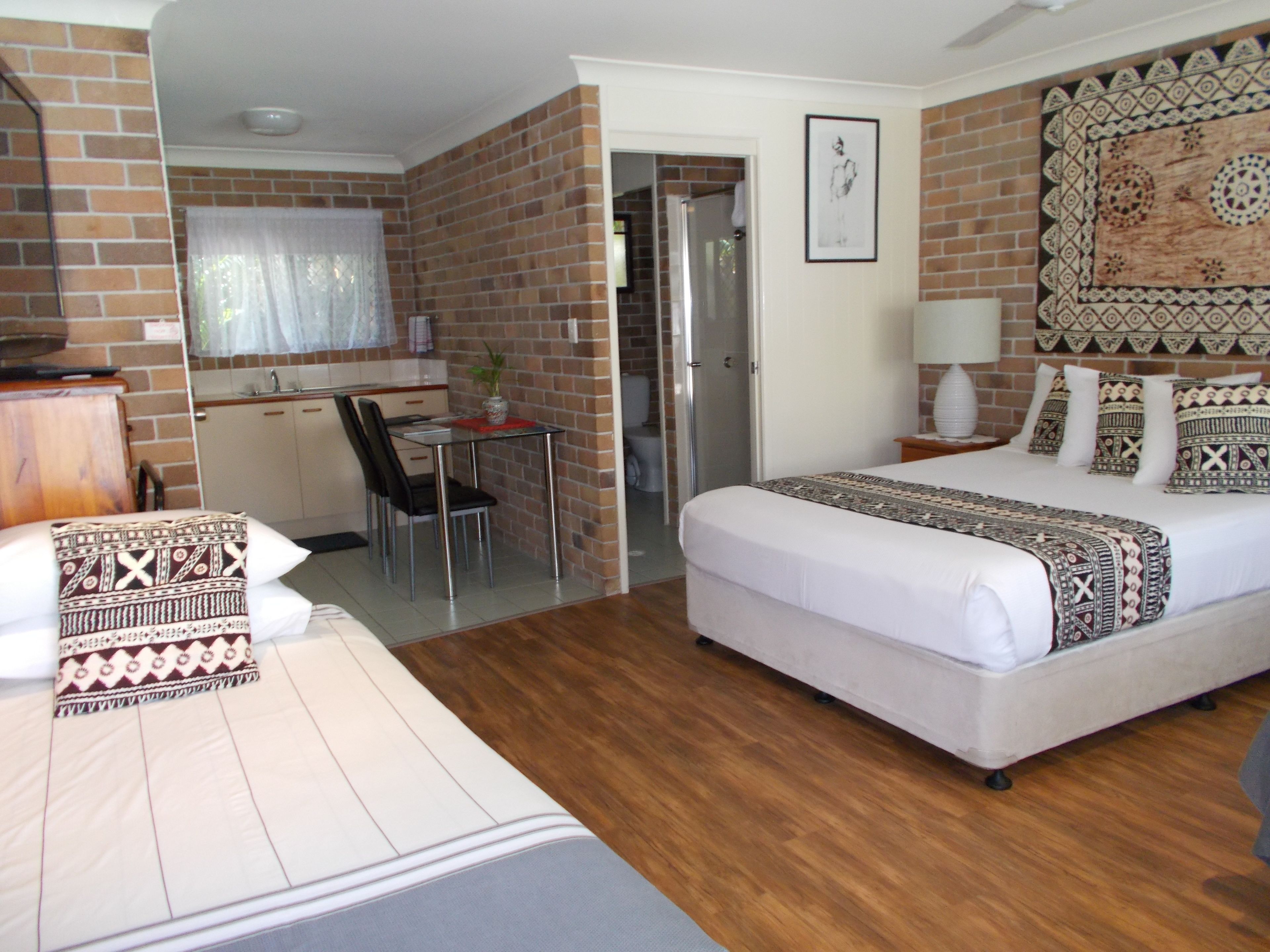Habitación de hotel con cama, un escritorio pequeño, una silla y un baño visible a través de una puerta abierta.