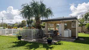A patio area with a covered seating area, a pool, and a fenced garden.