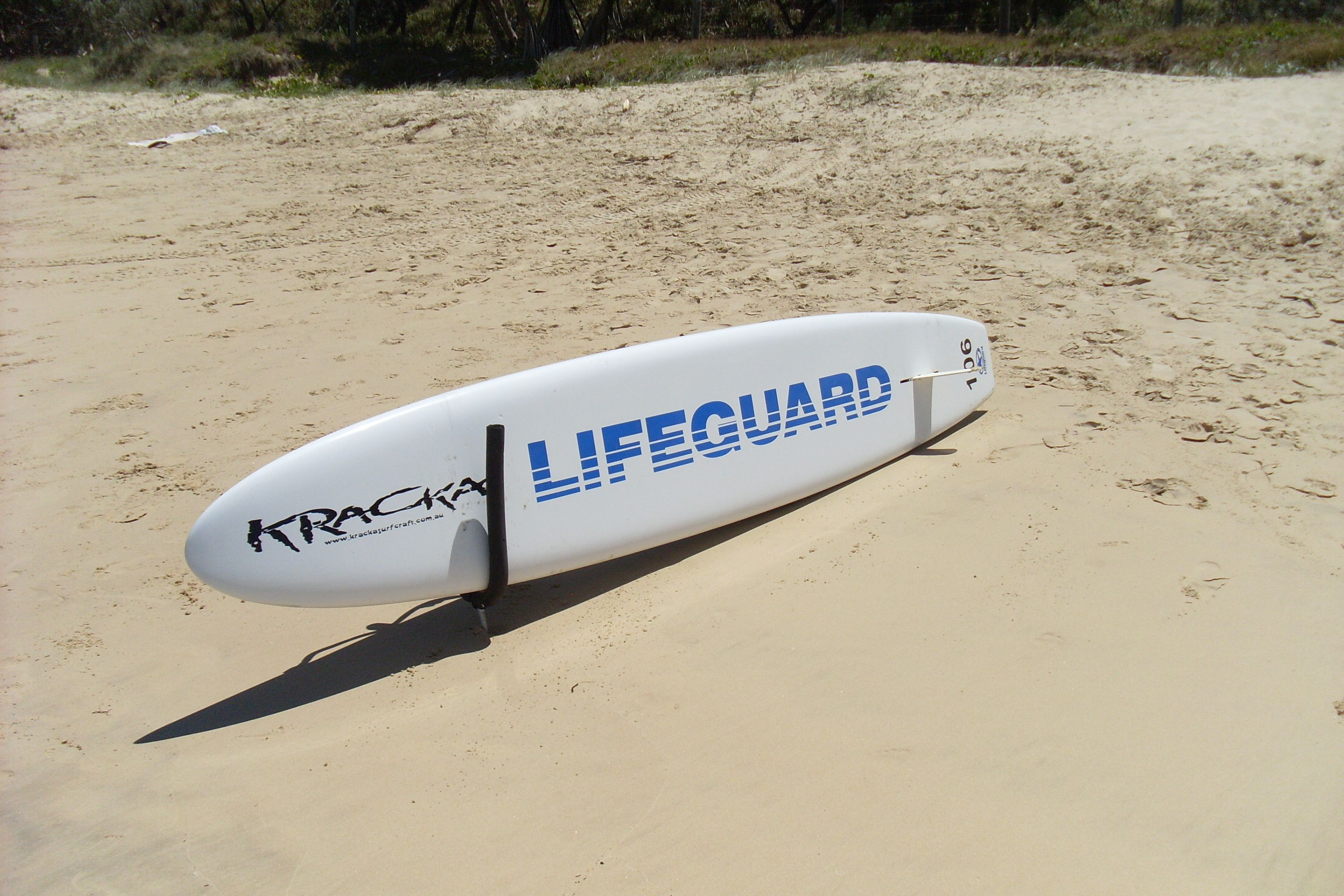 Une planche de surf utilisée par un sauveteur sur une plage de sable.