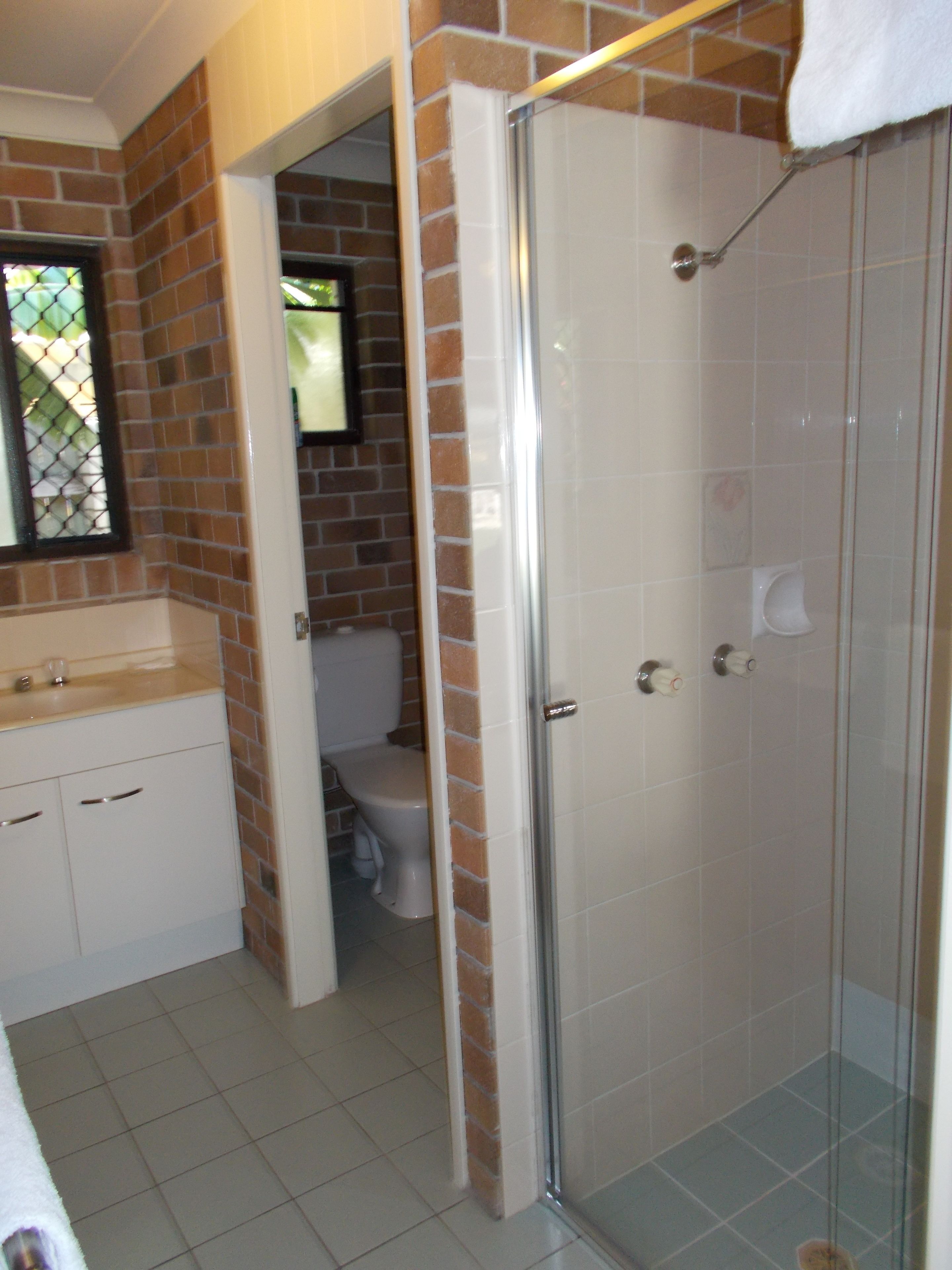 A bathroom with a shower, a toilet, and a sink.