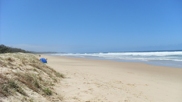 A beach with a dune and a tent.