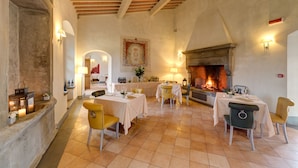 Un espace repas avec des tables et des chaises, une cheminée et des appliques murales.