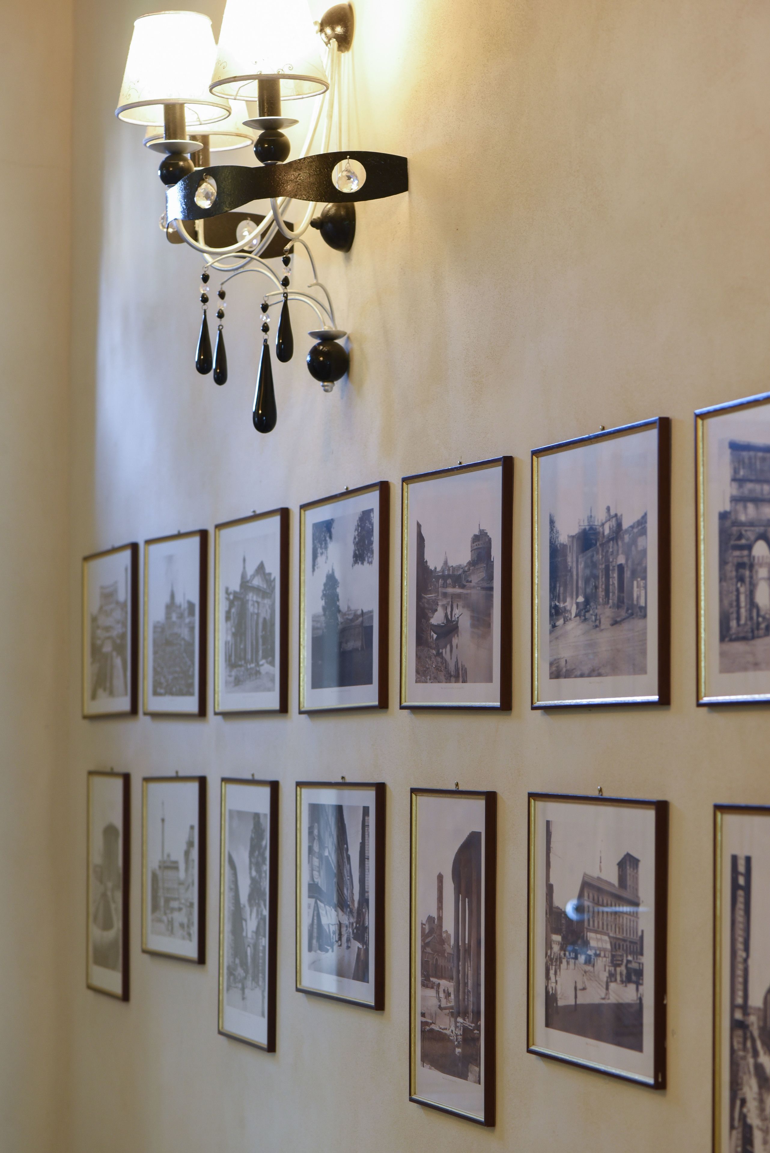 A wall with framed black and white photographs of various buildings and landmarks.