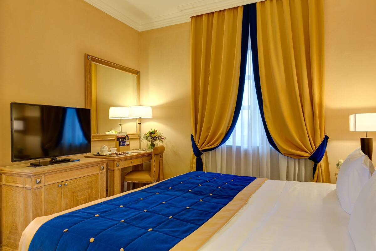 A hotel room with a bed, a television, a desk, and a chair.