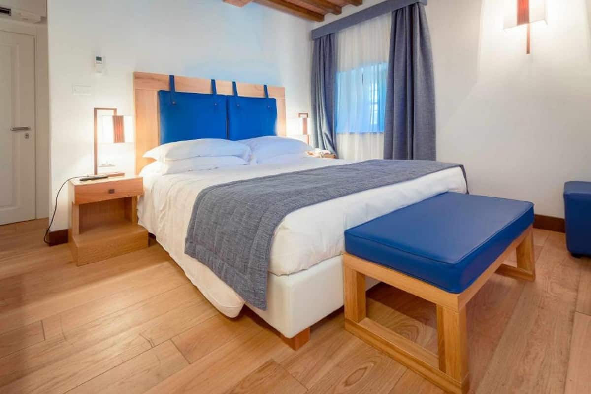 A bedroom with a bed, bedside tables, a bench, and a window with curtains.