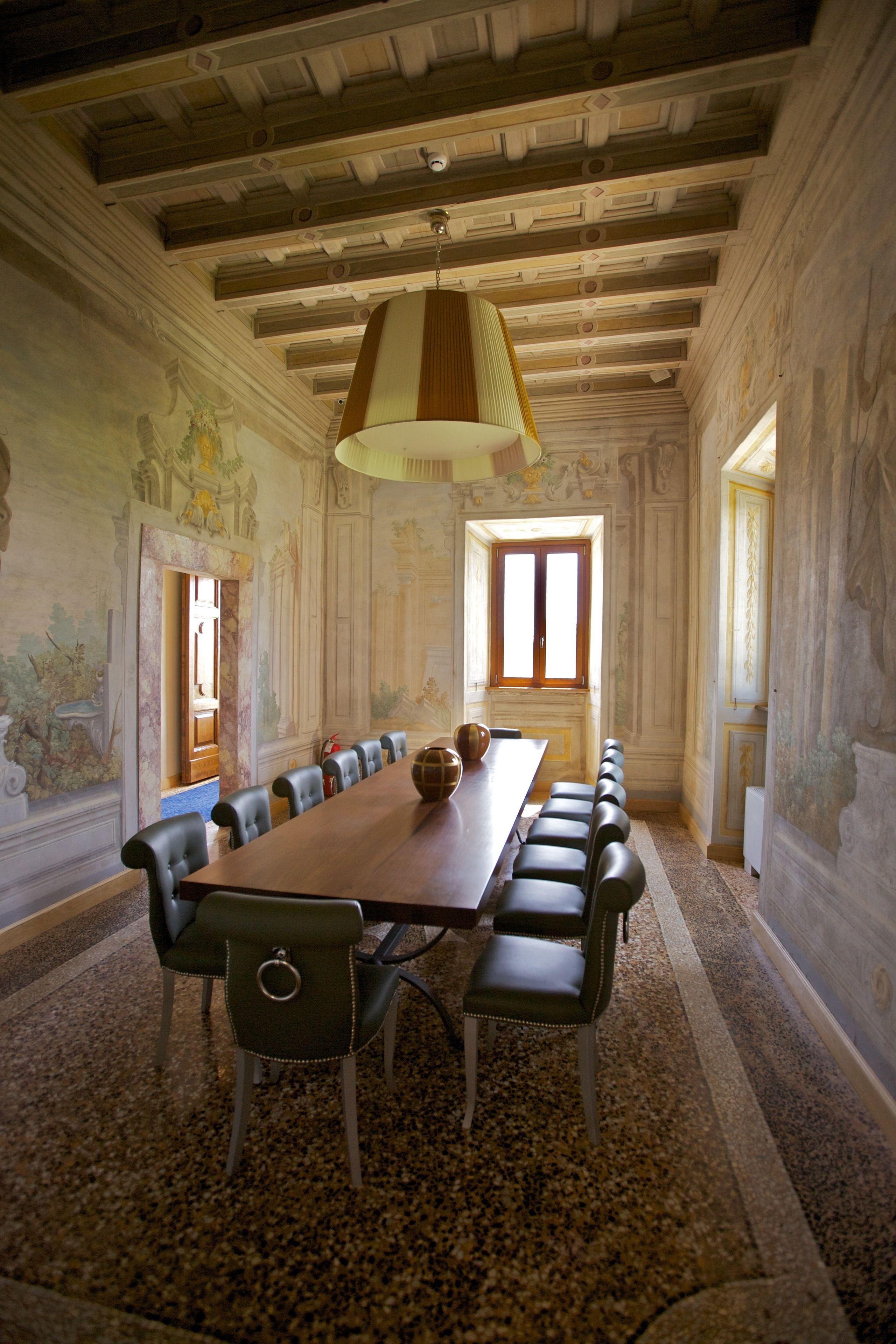 Una sala conferenze con un lungo tavolo, sedie e un lampadario.