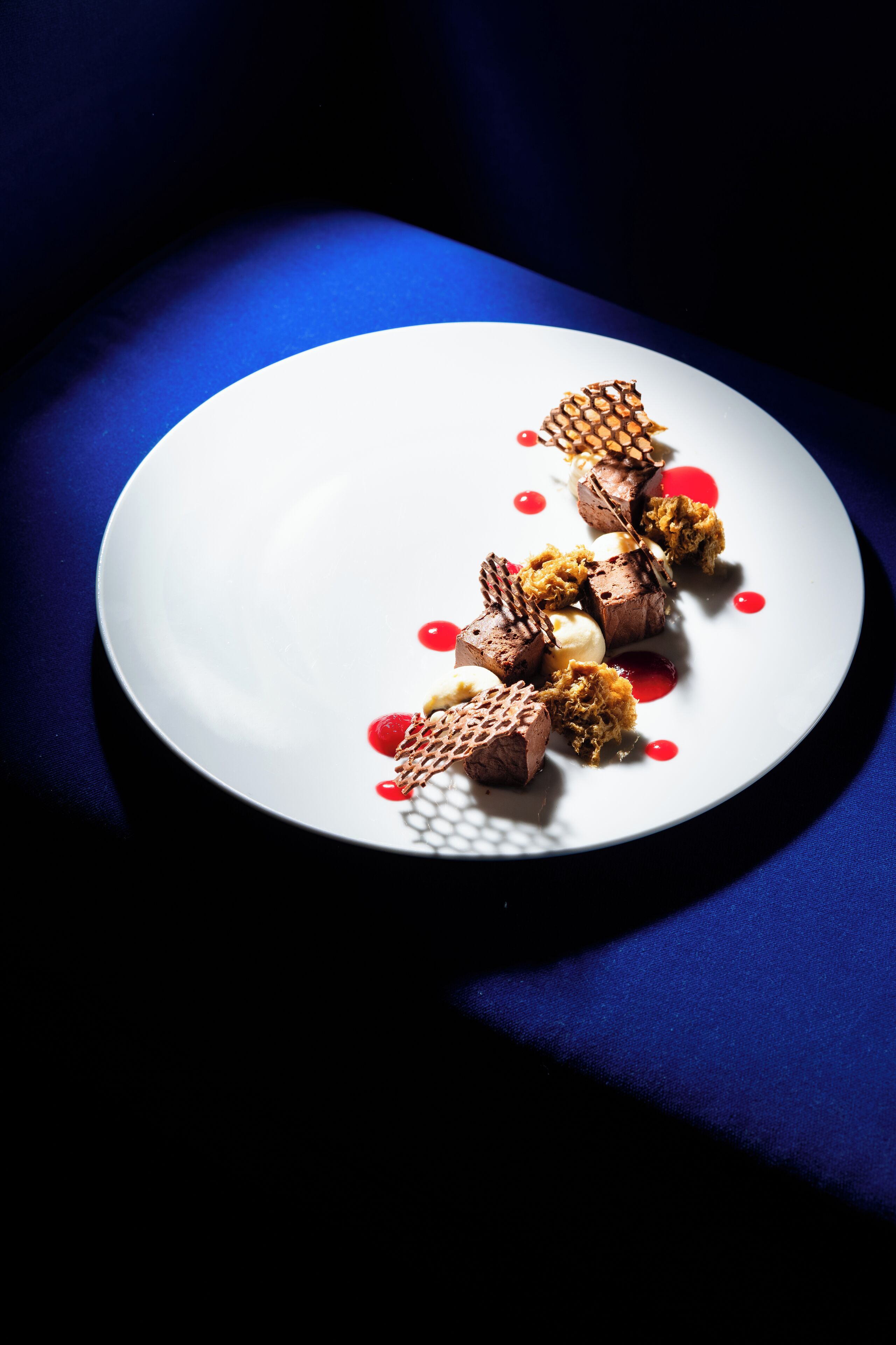 Un plato blanco con un postre sobre una superficie azul.