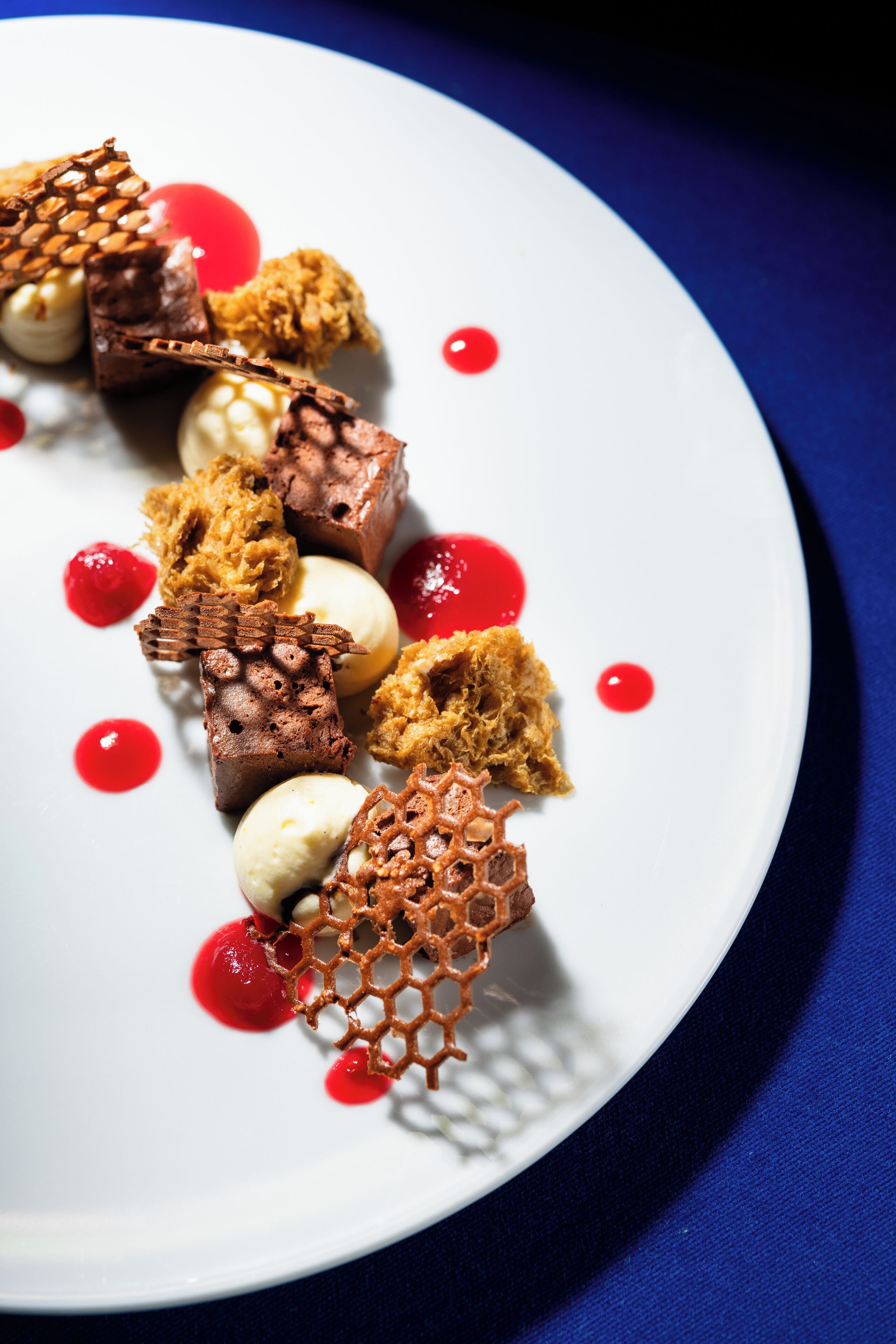 Un plato de postres con diferentes dulces y salsa roja.