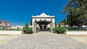 Un bâtiment doté d’une entrée abritée, de piliers en pierre et d’un chemin pavé menant à l’entrée.