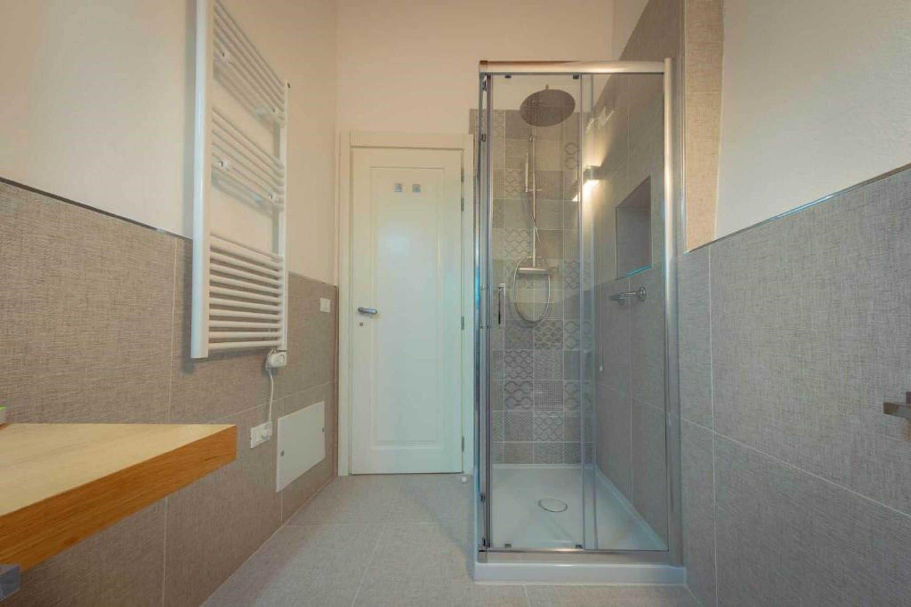 A modern bathroom with a glass-enclosed shower, a towel rack, and a wooden vanity.