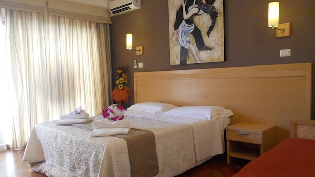 A hotel room with a large bed, a nightstand, a wall-mounted lamp, and a painting. - Catania Crossing B&B Rooms and Comforts (Catania)