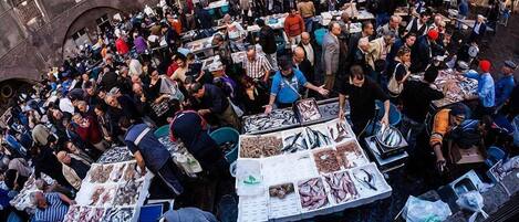 A crowded outdoor market with various stalls selling fish and other goods.