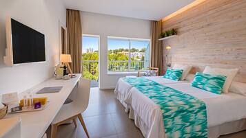 A modern hotel room with a large bed, a desk, a TV, and a balcony with a view of the city.