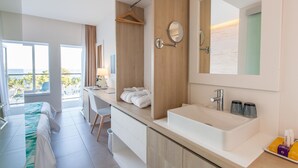 A modern hotel room with a large window, a wooden vanity with a sink, and a bed with a green and white bedspread. - FERGUS Style Palmanova - Adults Only (Calvia)