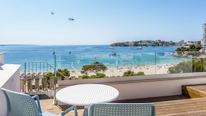 A balcony with a table and chairs overlooking a beach with boats and a clear sky. - FERGUS Style Palmanova - Adults Only (Calvia)