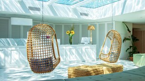 A modern room with a glass ceiling, wicker chairs, a sofa, and a desk with a lamp and flowers. - FERGUS Style Palmanova - Adults Only (Calvia)