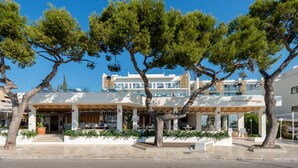A modern building with a covered outdoor seating area, surrounded by trees. - FERGUS Style Palmanova - Adults Only (Calvia)