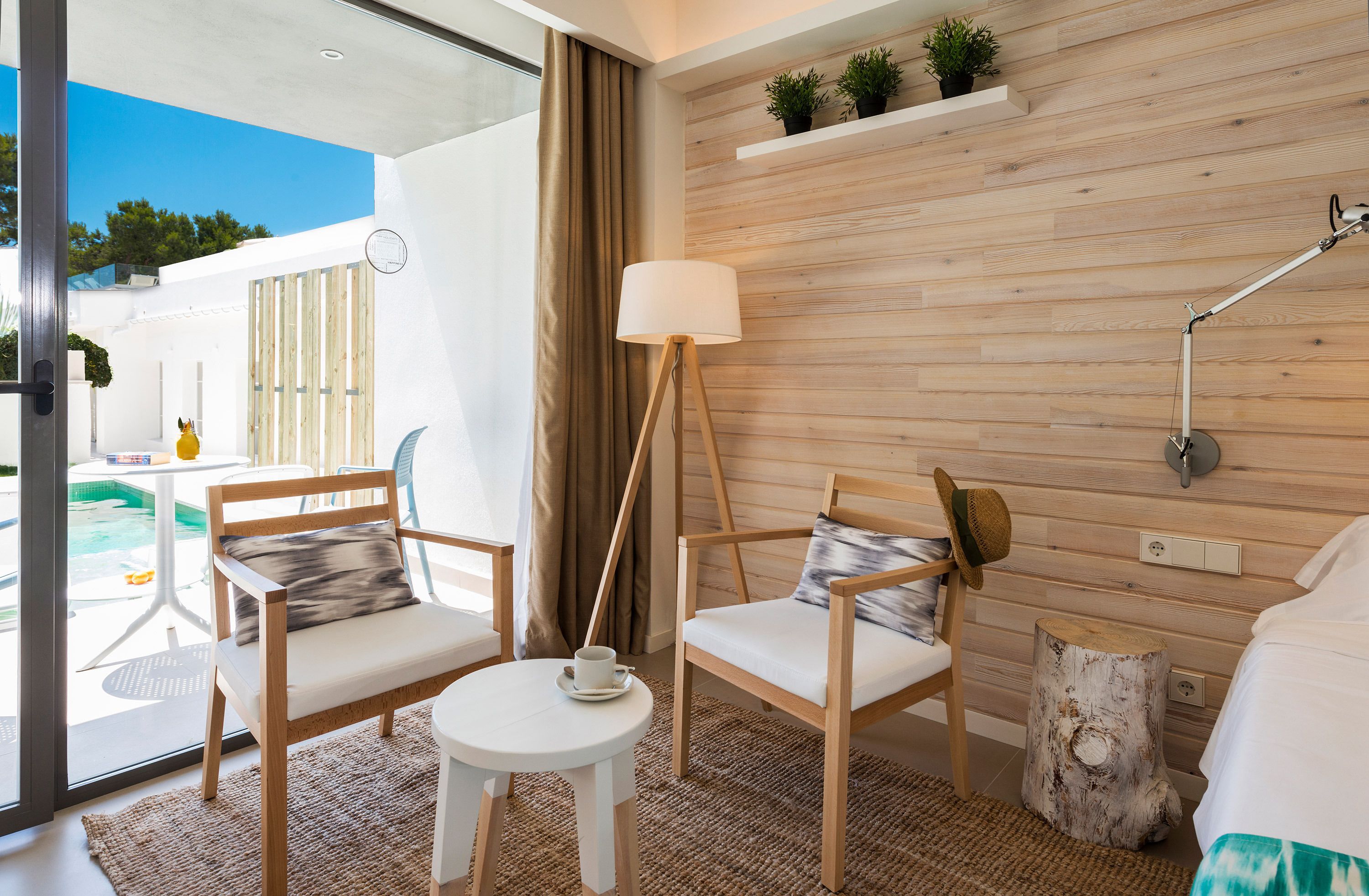 Een moderne kamer met een houten wand, een ronde tafel met stoelen, een lamp en een bed.
