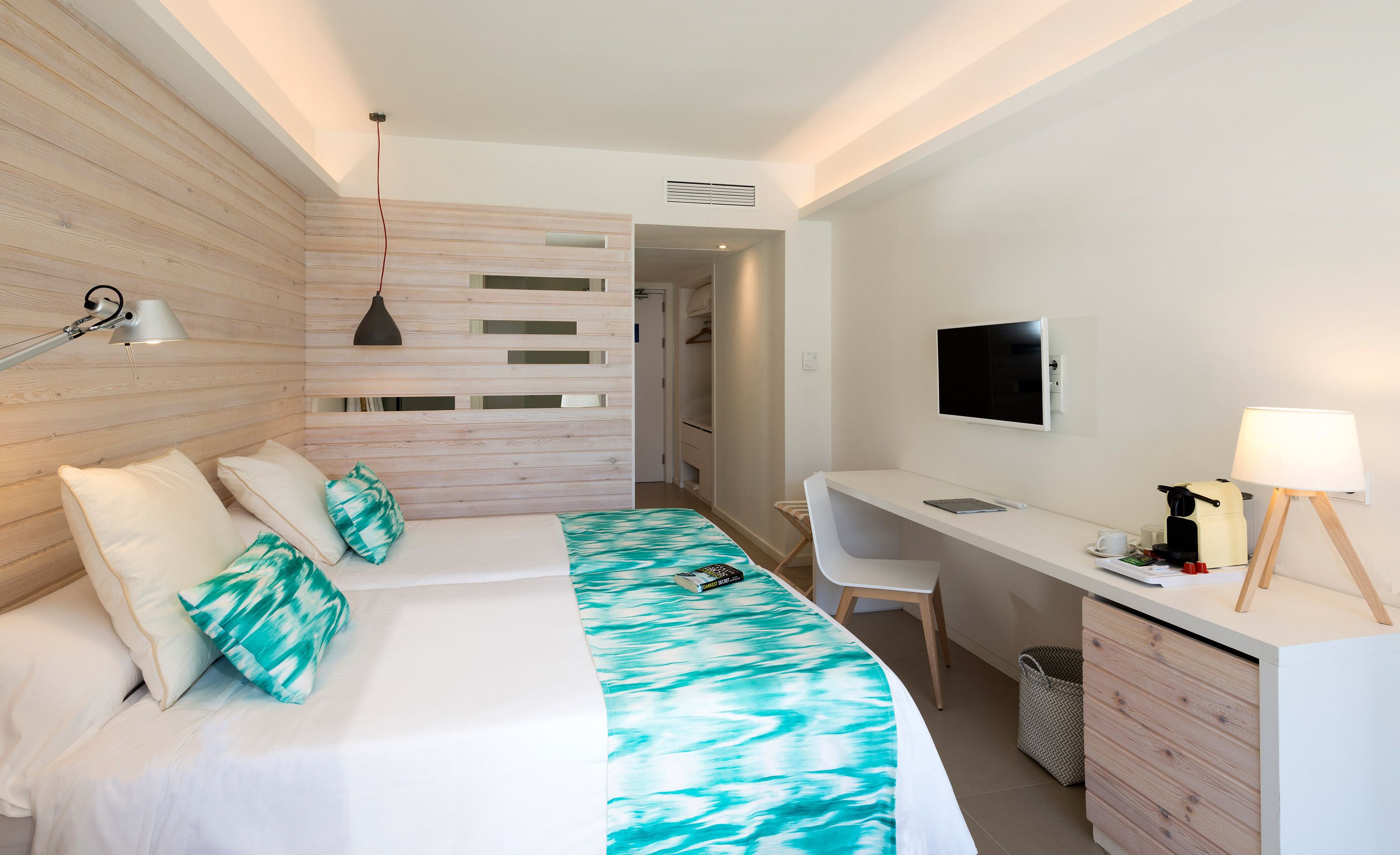 Une chambre d’hôtel moderne équipée d’un lit, d’un bureau et d’une télévision.