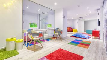 A modern, well-lit room with a large mirror, a desk with a computer, colorful rugs, and a cozy seating area with chairs.
