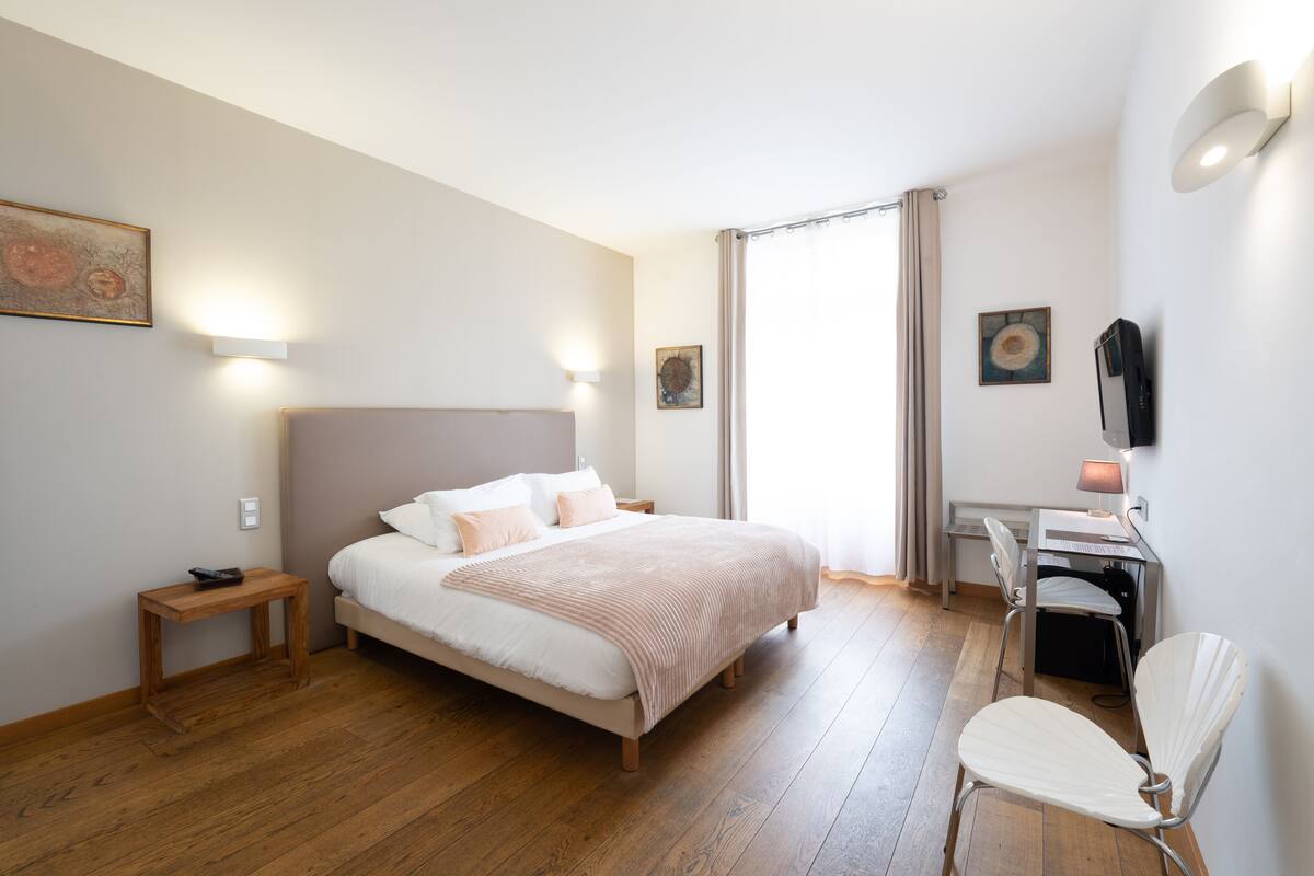 Ein Schlafzimmer mit Bett, Nachttisch, Schreibtisch, Stuhl und Bildern an den Wänden.