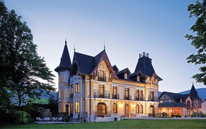 A large, ornate building with multiple towers and a well-maintained garden. - Le Manoir D Agnès (Tarascon-sur-Ariege)