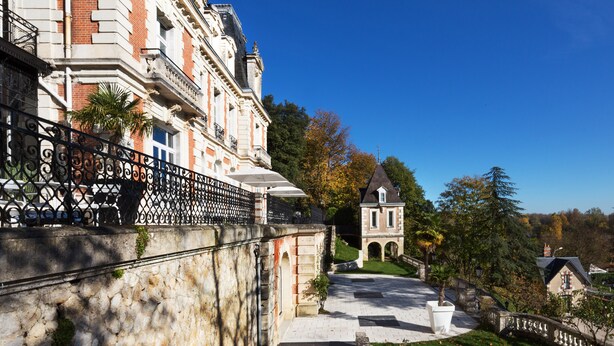A historic building with a stone facade, a paved courtyard, and a small tower. - Art Hôtel Rochecorbon (Rochecorbon)