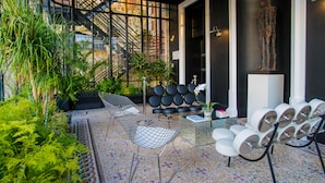 A modern interior with a seating area featuring a sofa and chairs, a small table with a book, and a decorative statue. - Art Hôtel Rochecorbon (Rochecorbon)
