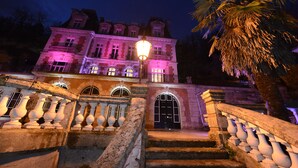 A grand building with a symmetrical facade, large arched windows, and a central entrance with a black door. - Art Hôtel Rochecorbon (Rochecorbon)