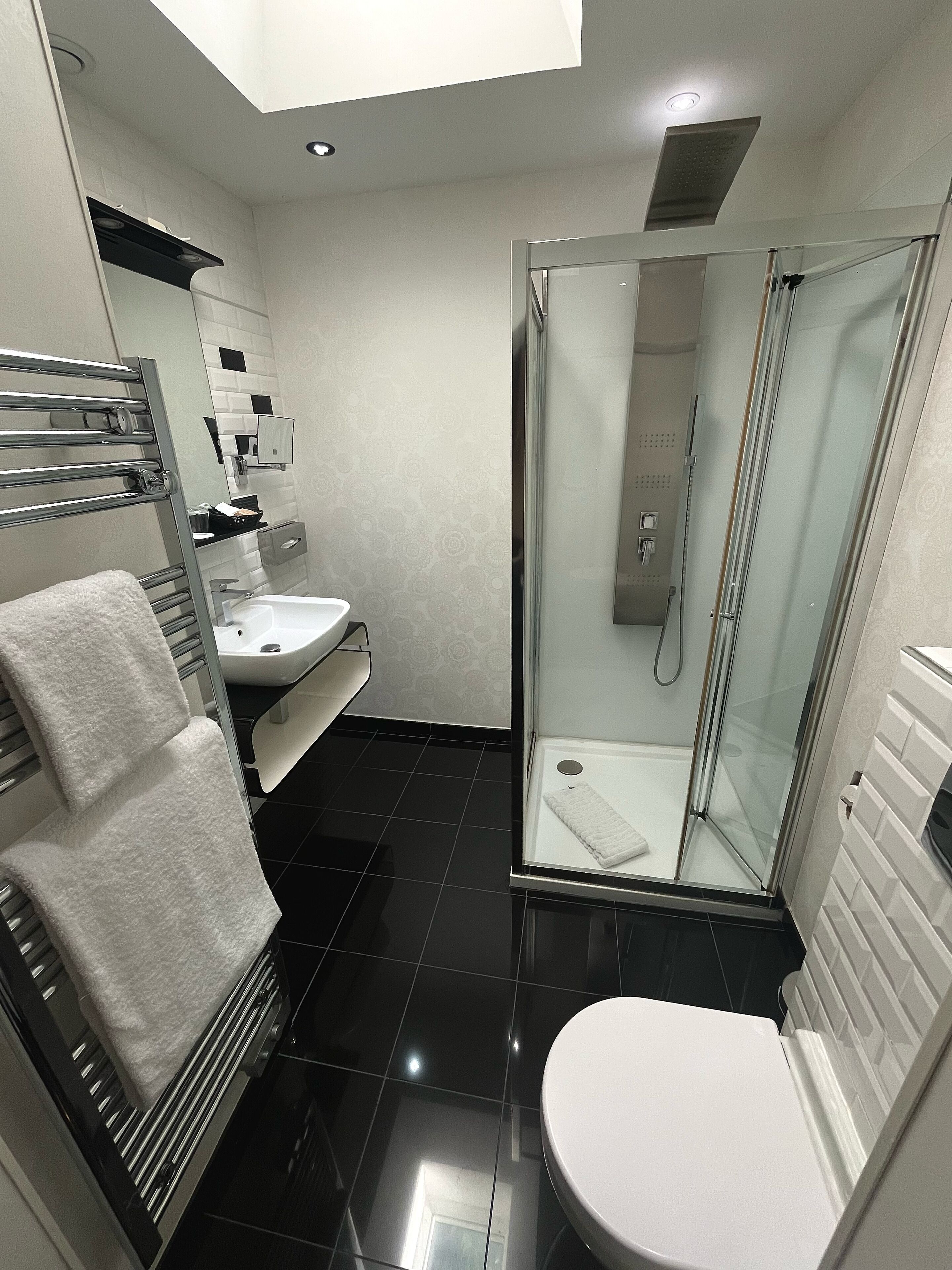 Une salle de bain moderne avec une douche à parois de verre, des toilettes blanches et un lavabo avec un miroir au-dessus.