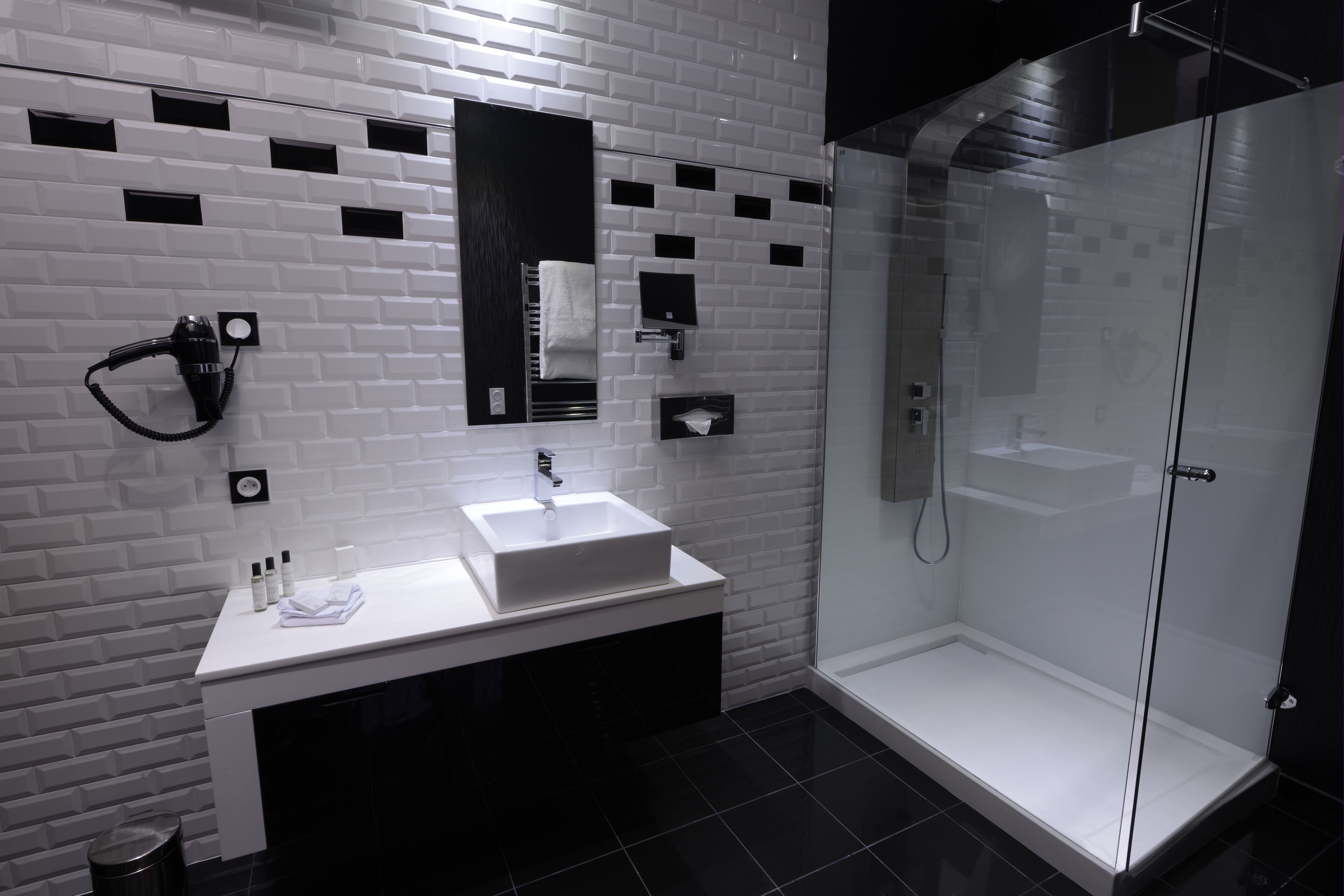 A modern bathroom with a white sink, a mirror, and a glass-enclosed shower.