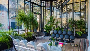 A conservatory with a glass ceiling, seating areas, and potted plants. - Art Hôtel Rochecorbon (Rochecorbon)