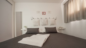 A neatly made bed with a folded white towel, two pillows, and a wall with three framed quotes. - Apartamentos Miami (Mogan)
