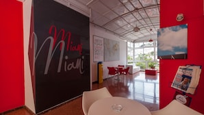 A modern interior with a red accent wall, a blackboard with 'Miami' written on it, a map, and a framed picture of clouds. - Apartamentos Miami (Mogan)