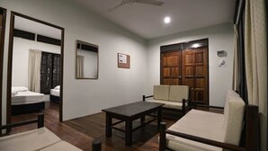 Una habitación con cama, sofá, mesa y puerta de madera.