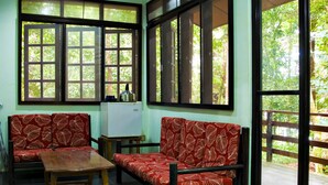 Una habitación con un conjunto de sofás, una mesita y ventanas amplias con vistas a zonas verdes.