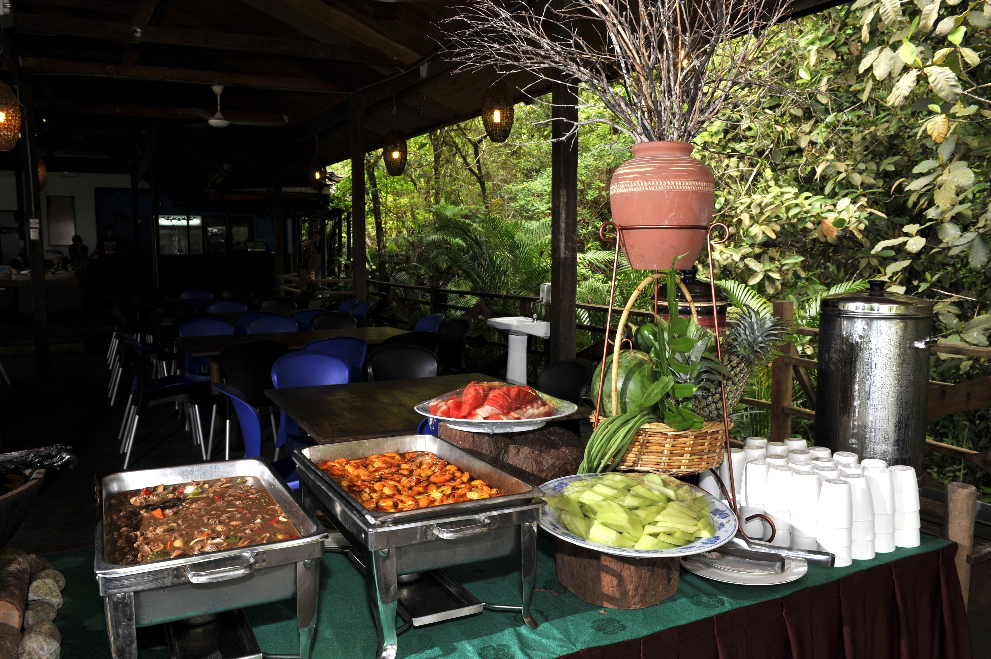 A buffet setup with various food items and a large terracotta pot.