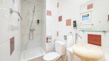 A modern bathroom with a glass shower enclosure, a white toilet, and a large oval sink.