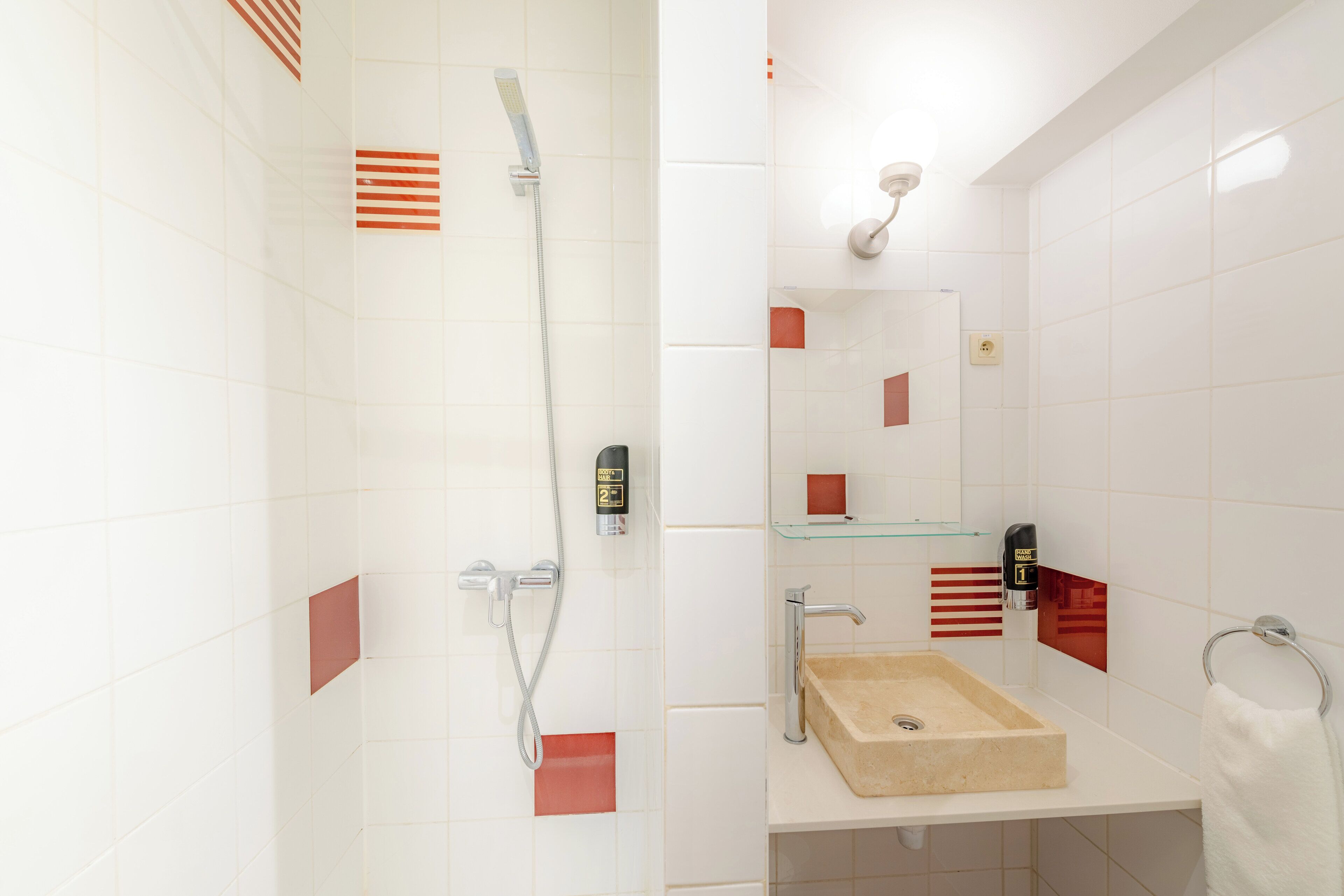 A modern bathroom with a glass shelf, a beige sink, and a handheld showerhead.