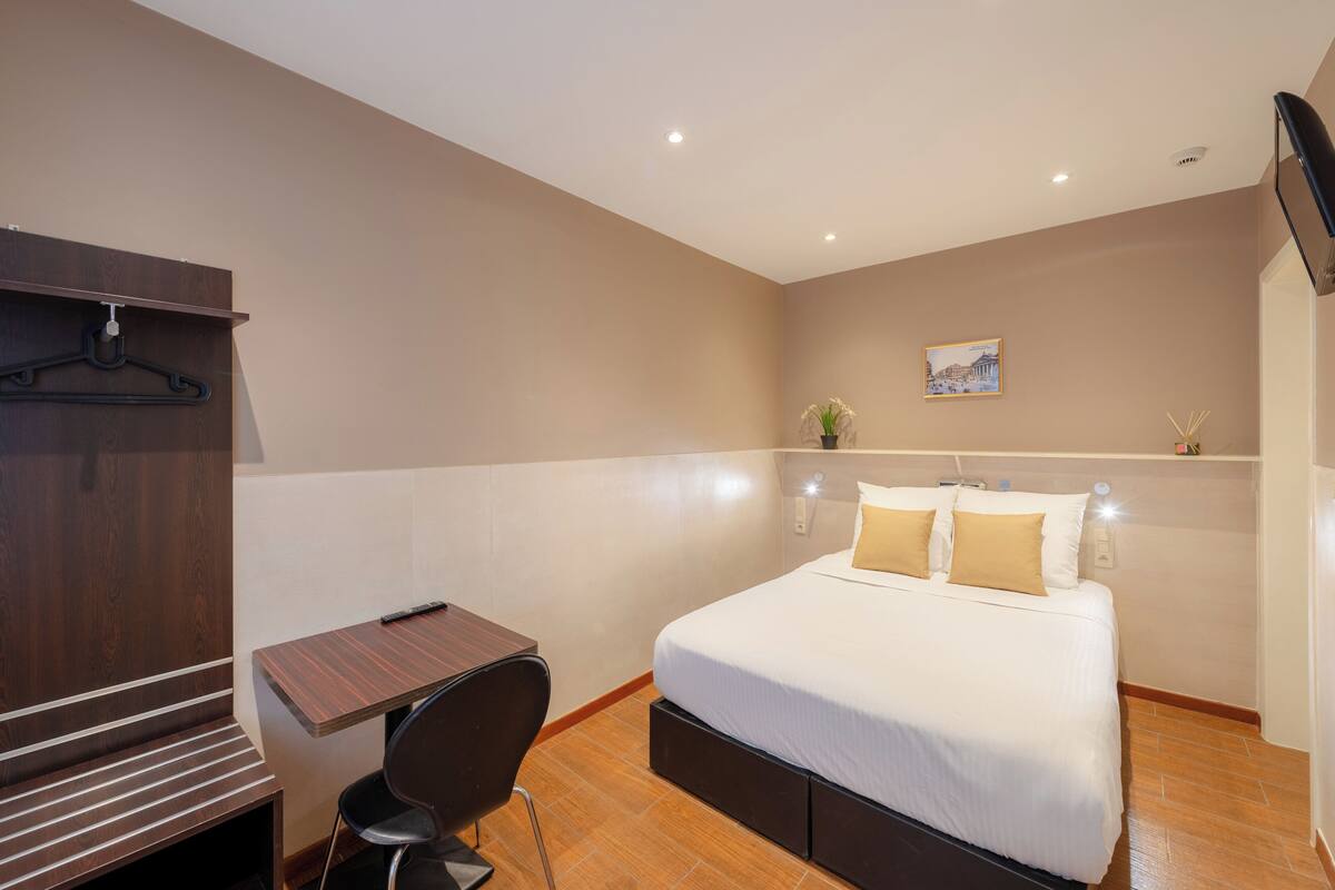 A bedroom with a bed, a desk, and a chair.