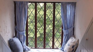 A window seat with a patterned cushion, curtains, and a view of greenery. - Church Villa B&B (Chesterfield)