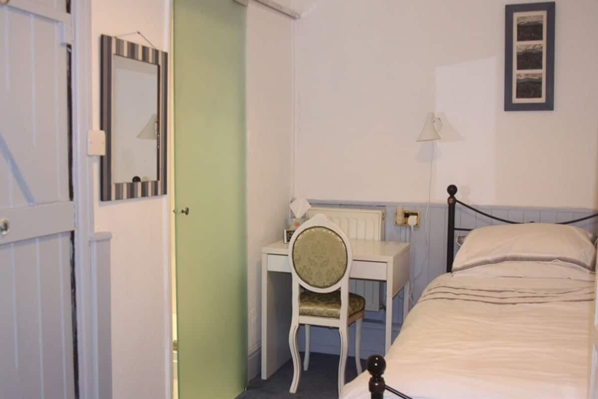 A bedroom with a bed, a desk, and a chair.