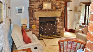 A cozy living room with a brick fireplace, a sofa, a chair, and a small table. - Church Villa B&B (Chesterfield)
