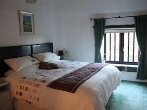A bedroom with a bed, a nightstand, a window with curtains, and a wall-mounted picture. - Church Villa B&B (Chesterfield)